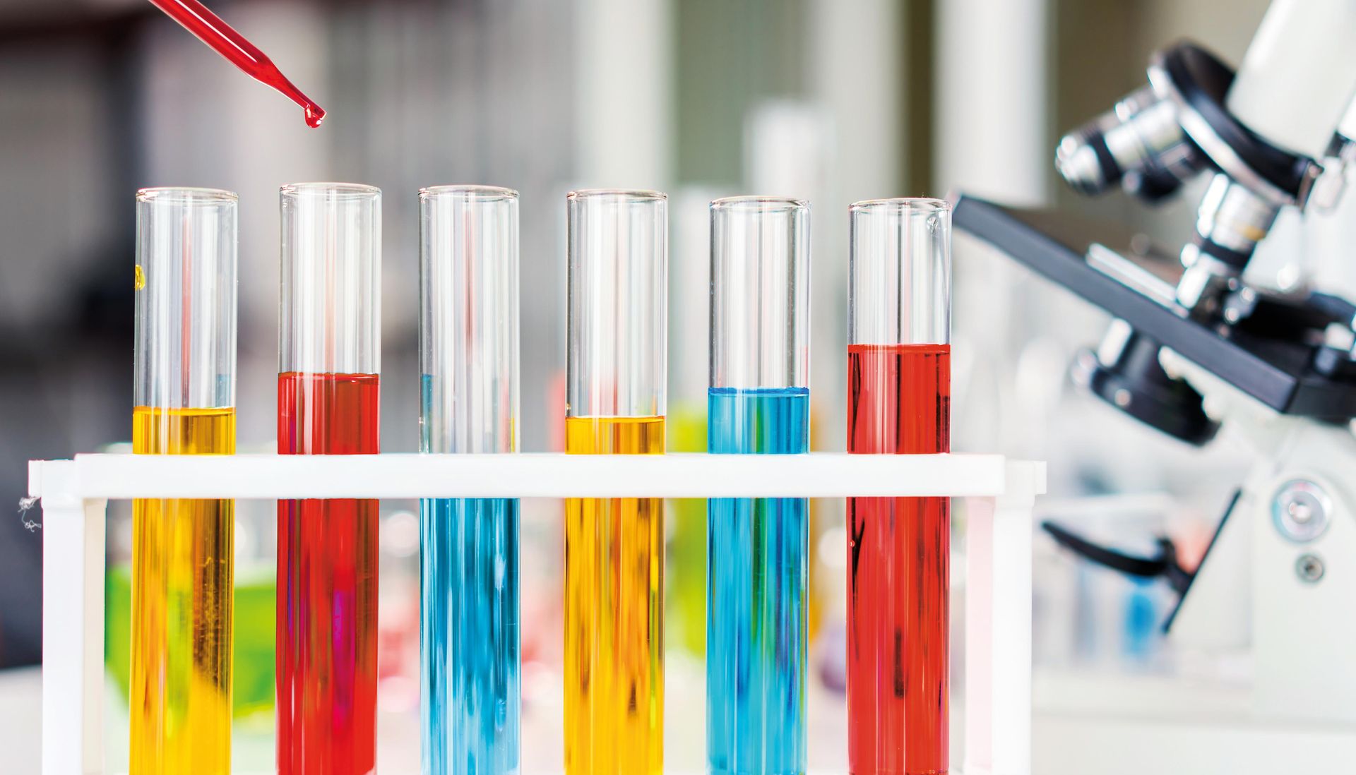 Test tubes are filled with red, yellow and blue liquids representing chemicals for evaluation and registration in the REACH context.